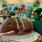 Capivara de pelúcia com roupa colorida e arranjo verde na decoração de festa infantil. 2