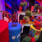 Detalhes da decoração do Homem-Aranha com miniaturas, balões azuis e vermelhos e cilindros temáticos.
