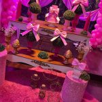 Decoração infantil rosa com laços de cetim, mesas decoradas, balões e arranjos florais.