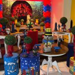 Vista frontal da decoração dos Vingadores com painel da Marvel, balões vermelhos e azuis e mesa de aniversário com super-heróis.