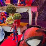 Máscara do Homem-Aranha em destaque com bonecos, prédios em miniatura e decoração de aniversário.