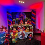 Mesa de aniversário do Homem-Aranha com bonecos, cilindros coloridos e elementos de histórias em quadrinhos.