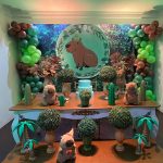 Decoração de aniversário infantil com tema capivara, painel tropical, balões verdes e mesa decorada.